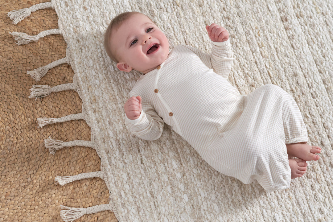 An adorable baby girl in a white dress, enjoying a cozy nap on a comfy rug.