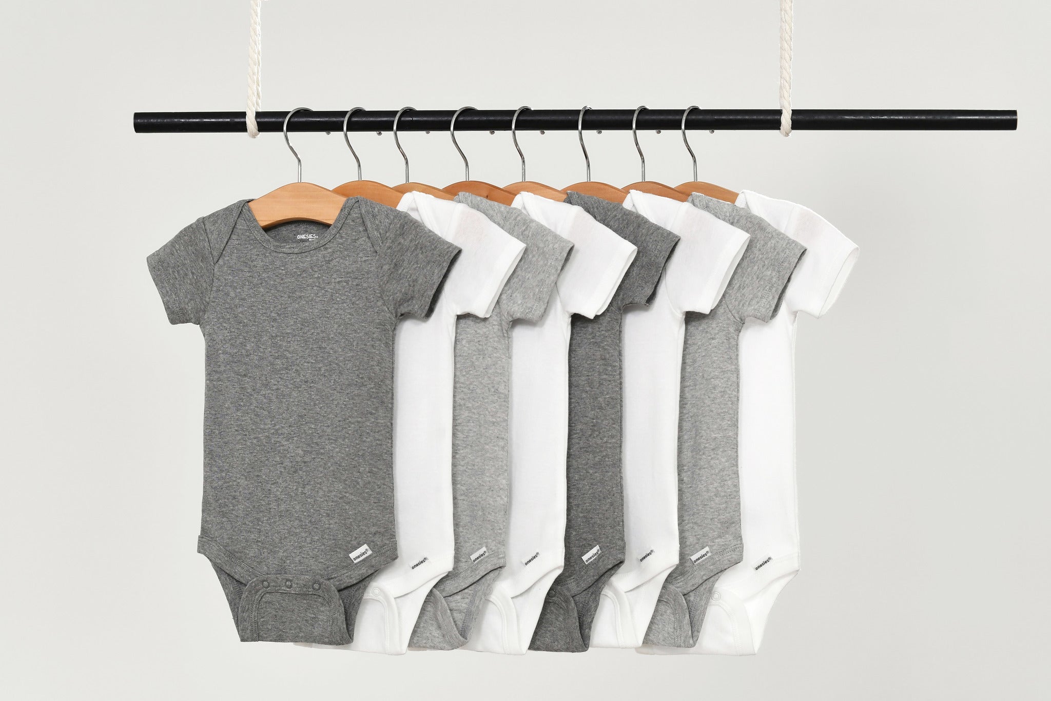 Grey and white onesies hanging on a rod.
